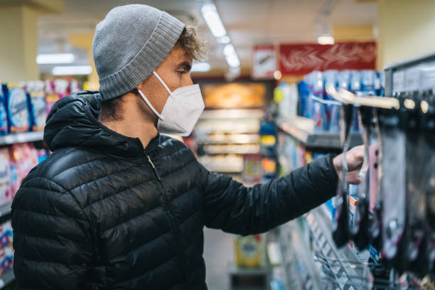 istock Young man wearing protective face mask shops in grocery store 1290877734