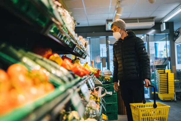 istock Young man wearing protective face mask shops in grocery store 1290877836