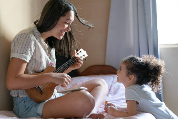 tante spielt ukulele für nichte - nursery rhyme stock-fotos und bilder
