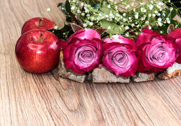 Flowers with apples on a wooden background.