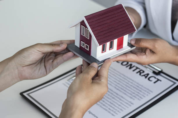 istock Close-up Second hand people holding small house model, Real Estate concept. 1290880030