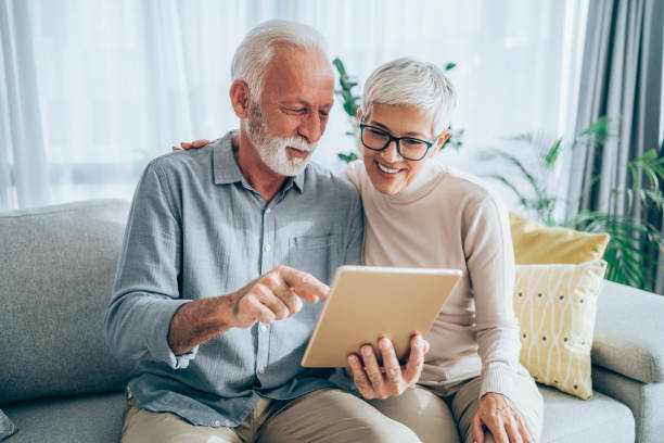 Relaxing at home with wireless technology. Mature couple sitting on the sofa at home and using digital tablet. couple isolated wife husband stock pictures, royalty-free photos & images