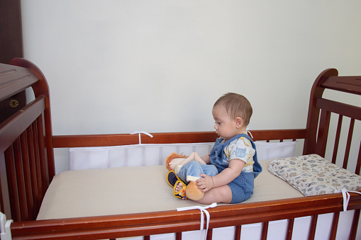 baby sitting in wooden crib