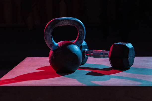 istock Kettlebell and dumbbell in red-blue gradient light on dark background 1290882807