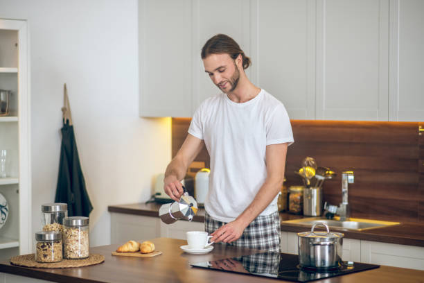 istock Young man in homewear preparing breakfast in the kitchen 1290884191