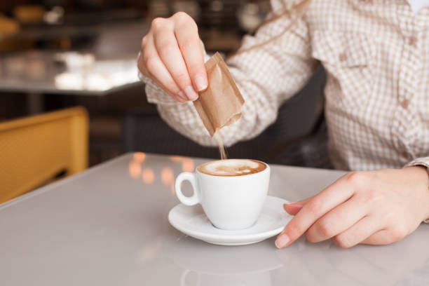 istock Woman's hands pouring sugar into coffee or tea 1290885078