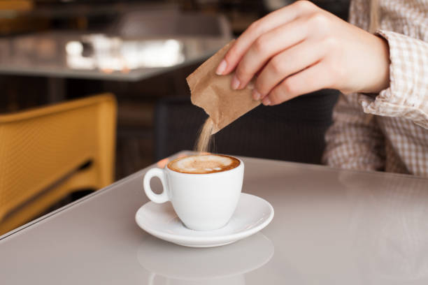 mani della donna che versano zucchero nel caffè - sugar sachet foto e immagini stock