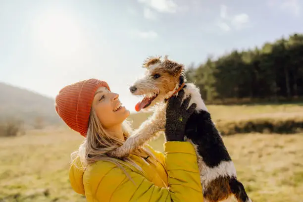 Photo of a young woman taking a break from running to pet her fox terrier, who keeps her company during exercise