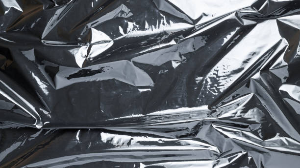 istock Smooth texture. Black shiny film bag pattern. Wrap transparent dark cellophane background. Real texture of polyethylene foil. 1290890559