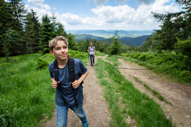 Mother with son are hiking on the path on beautiful hills.\nNikon D850