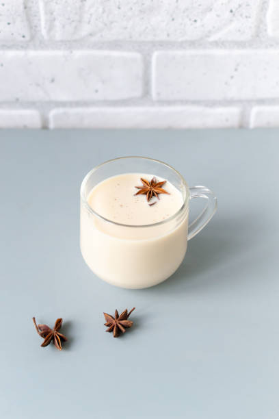 Glass cup of Masala tea with spices and anise stars on a gray background. stock photo