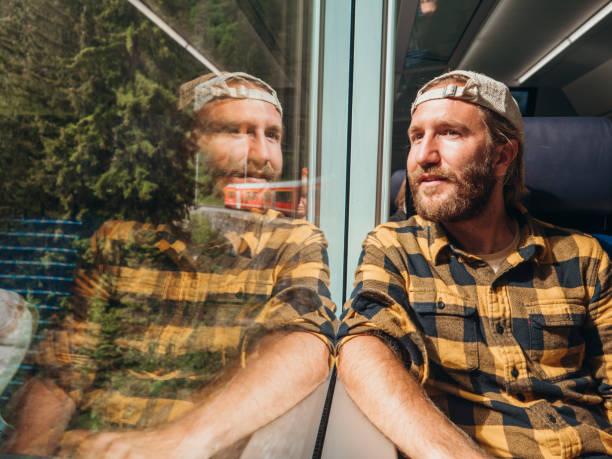 istock Man traveling by train looking from the window enjoying passing scenery, reflection on glass 1290893396