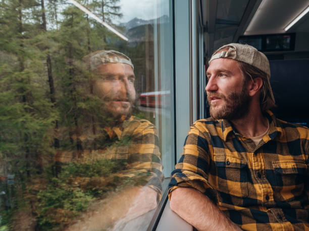 istock Man traveling by train looking from the window enjoying passing scenery, reflection on glass 1290894126