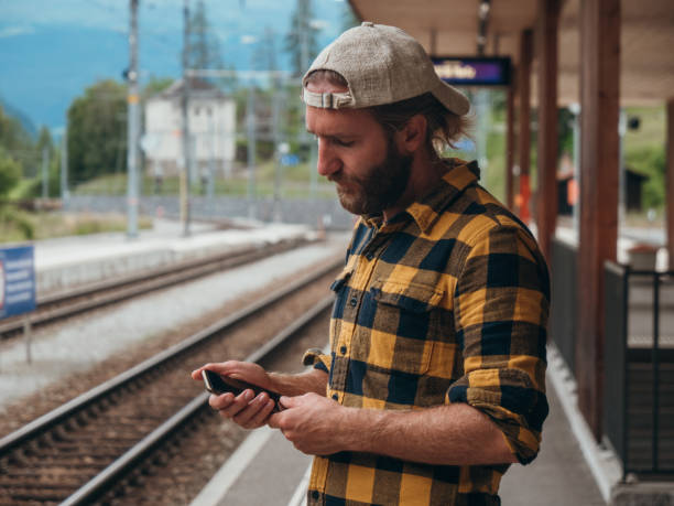 istock Man checks phone at train station 1290894145