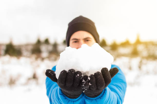 mãos de um homem de jaqueta azul segurando uma bola de neve em uma montanha de neve no inverno. stock photography - motivation passion cold inspiration - fotografias e filmes do acervo