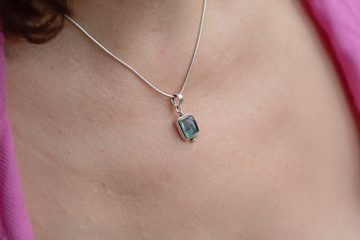 Detail of woman neckline wearing apatite mineral stone pendant on silver chain