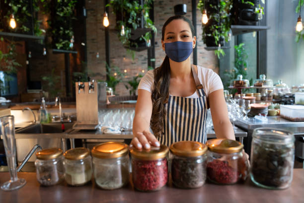 istock Waitress wearing a facemask while working behind the bar at a restaurant 1290900655