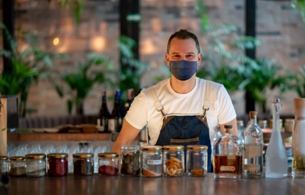 istock Waiter wearing a facemask while working behind the bar at a restaurant 1290900676