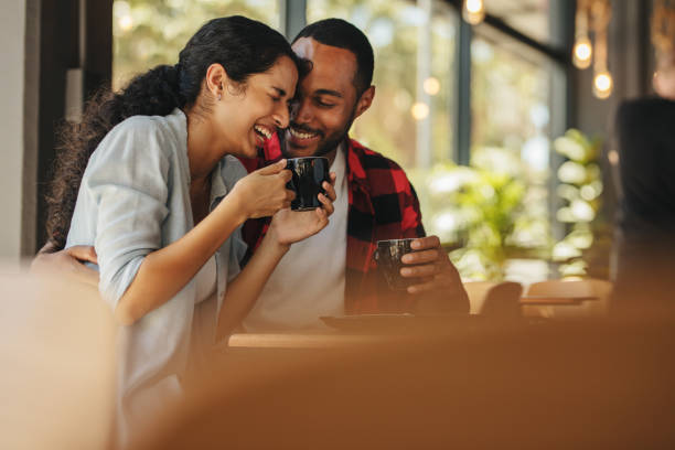 Couple talking over a cup of coffee at cafe Couple talking over a cup of coffee at cafe. Man and woman sitting at coffee shop having a conversation while having coffee. couple drinking stock pictures, royalty-free photos & images