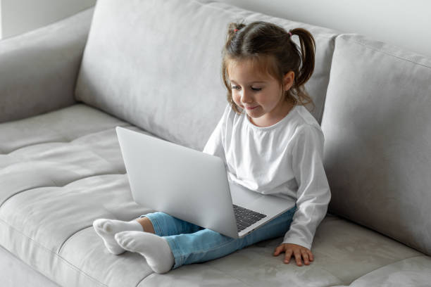 istock Little girl using laptop on sofa 1290907595