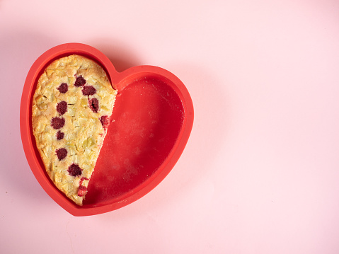 Heart shape half apple pie in silicon mould on pink background