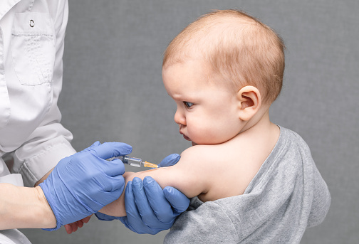 Portrait of baby girl receiving vaccination.