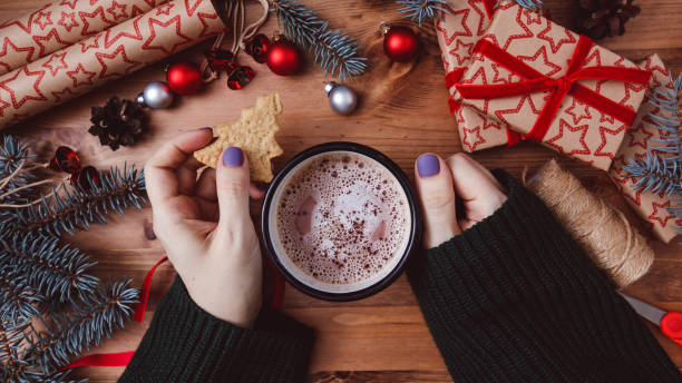 istock Women's hands hold a mug with hot cocoa on a wooden table. 1290912053
