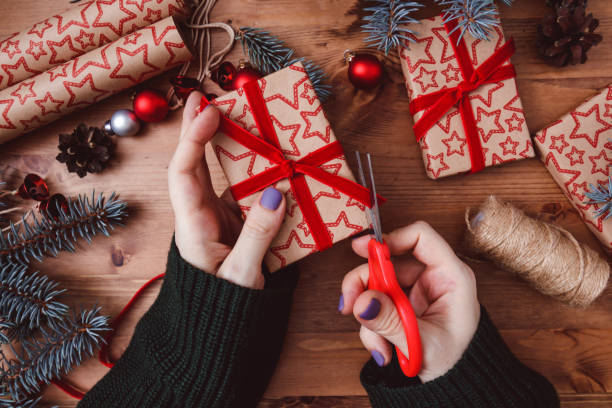 istock Women's hands are wrapping a Christmas gift a wooden background. 1290912056
