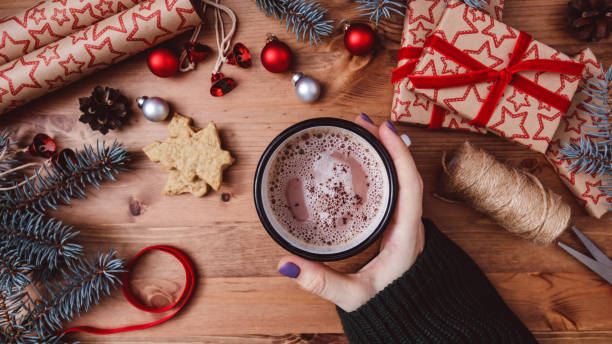istock Women's hands hold a mug with hot cocoa on a wooden table. 1290912580
