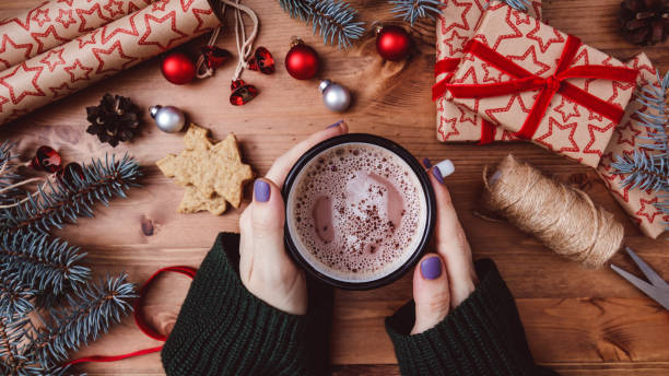 istock Women's hands hold a mug with hot cocoa on a wooden table. 1290912587