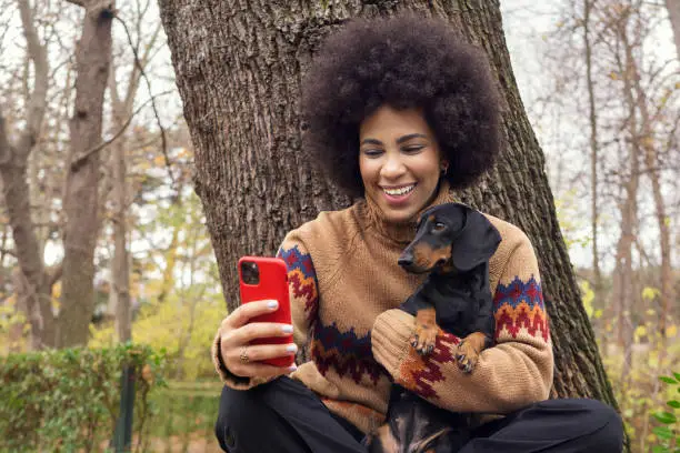 a Cuban girl taking a selfie with her dachshund in the park