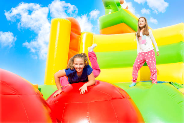 istock Two Girls Jumping on Inflatable Castle Playground 1290912935