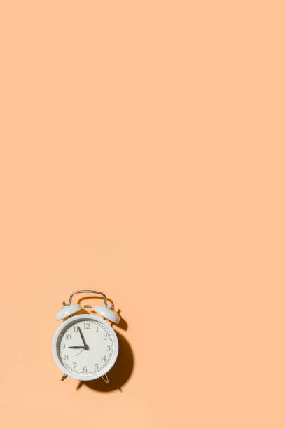 istock White alarm clock with bells on beige background 1290913065