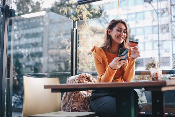 la giovane donna sta comprando online, usando il suo cellulare. concetto di covid-19. - carta di credito foto e immagini stock