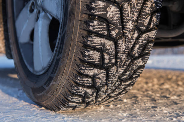 istock Car wheel with winter studded tread on snowy road. 1290917089