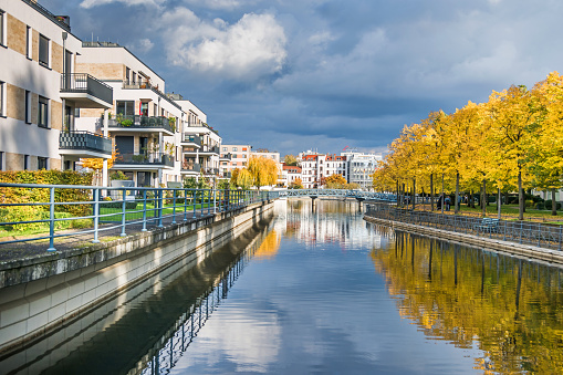 Berlin, Germany - October 24, 2020:  Harbor basin Tegeler Hafen with old and modern buildings,  residential units, footbridge and autumn coloured trees