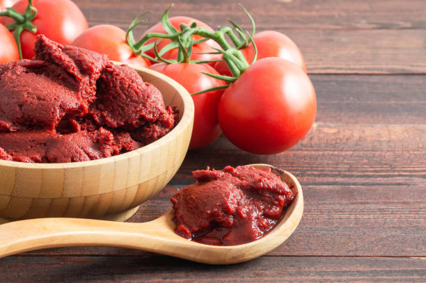 Traditional turkish tomato paste in bowl or spoon with fresh tomatoes on wooden table, homemade healthy food stock photo