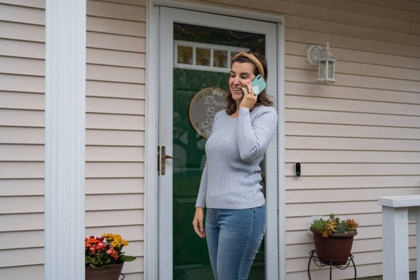 istock Woman using cellphone in front of her house 1290933256