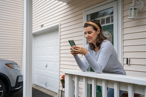 Woman using cellphone in front of her house