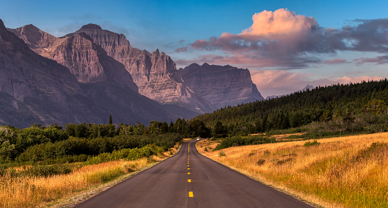 Beautiful View of Scenic Highway with American Rocky Mountain Landscape in the background. Colorful Summer Sunrise Sky. Taken in St Mary, Montana, United States.