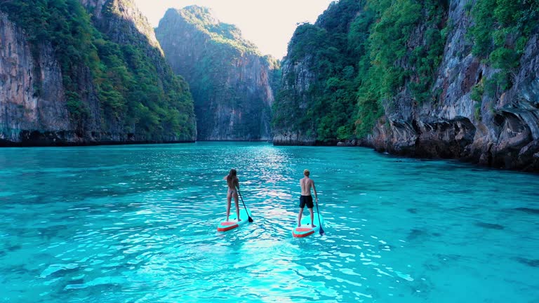 Tropical Vacation Activities :Aerial view of nice day,Young couple in love kayaking on sea together on a tropical climate.Holidays, Summer, Relaxation, Luxury, Pleasure, Happiness, Fun, Wonderlust, Adventure, Experience, Trip, Holidays, Togetherness, Relaxation, Love, Escape, Drone Point Of View, Moving Activity, Busy, Progress, Vitality concept.