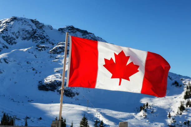 istock Canadian Flag with a winter mountain landscape 1290944126