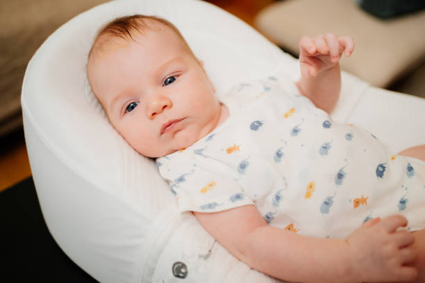 infant on a white lounger. seborrheic dermatitis on the baby's head. infant, a boy in a white bodysuit lying on a white lounger for newborns. seborrheic dermatitis on the baby's head. chaise longue stock pictures, royalty-free photos & images