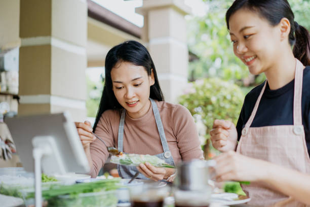 istock Two young asian women making Vietnamese spring rolls and using digital tablet for online recipe 1290950899