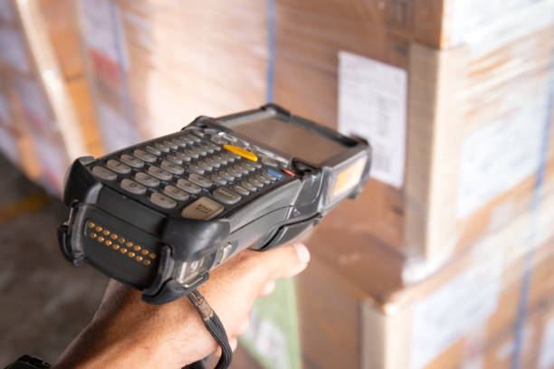 istock Close-up, hand of worker holding barcode scanner scanning cargo boxes. Computer equipment for warehouse inventory management. 1290956424