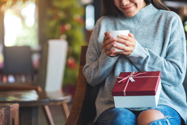 istock a beautiful young woman holding a gift box while drinking coffee 1290956559