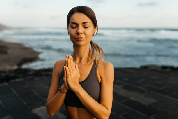 istock young beautiful woman meditation on beach. 1290958868