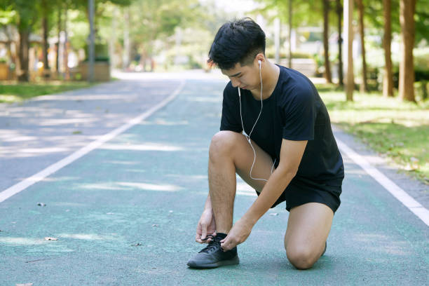 istock Sporty Man Tying Shoelace Before Jogging In Summer Park 1290960454