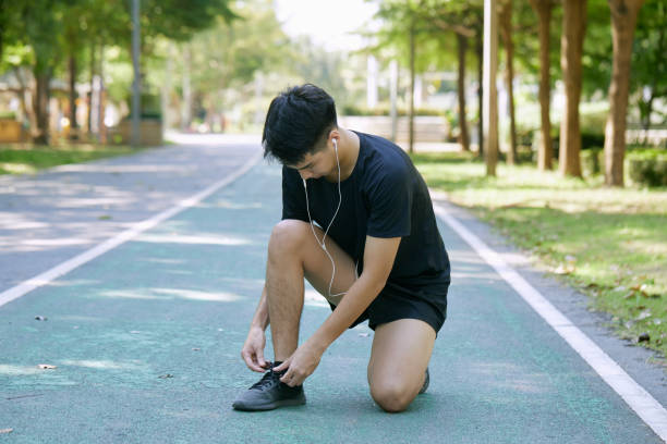 istock Sporty Man Tying Shoelace Before Jogging In Summer Park 1290960455