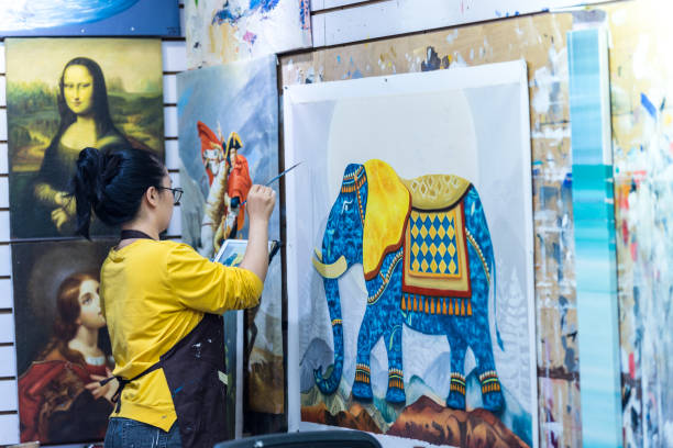 una artista femenina de pintura al óleo pintando sobre un lienzo en el pueblo de pintura al óleo de dafen, shenzhen, provincia de guangdong, china - contemporary editorial pattern architecture fotografías e imágenes de stock
